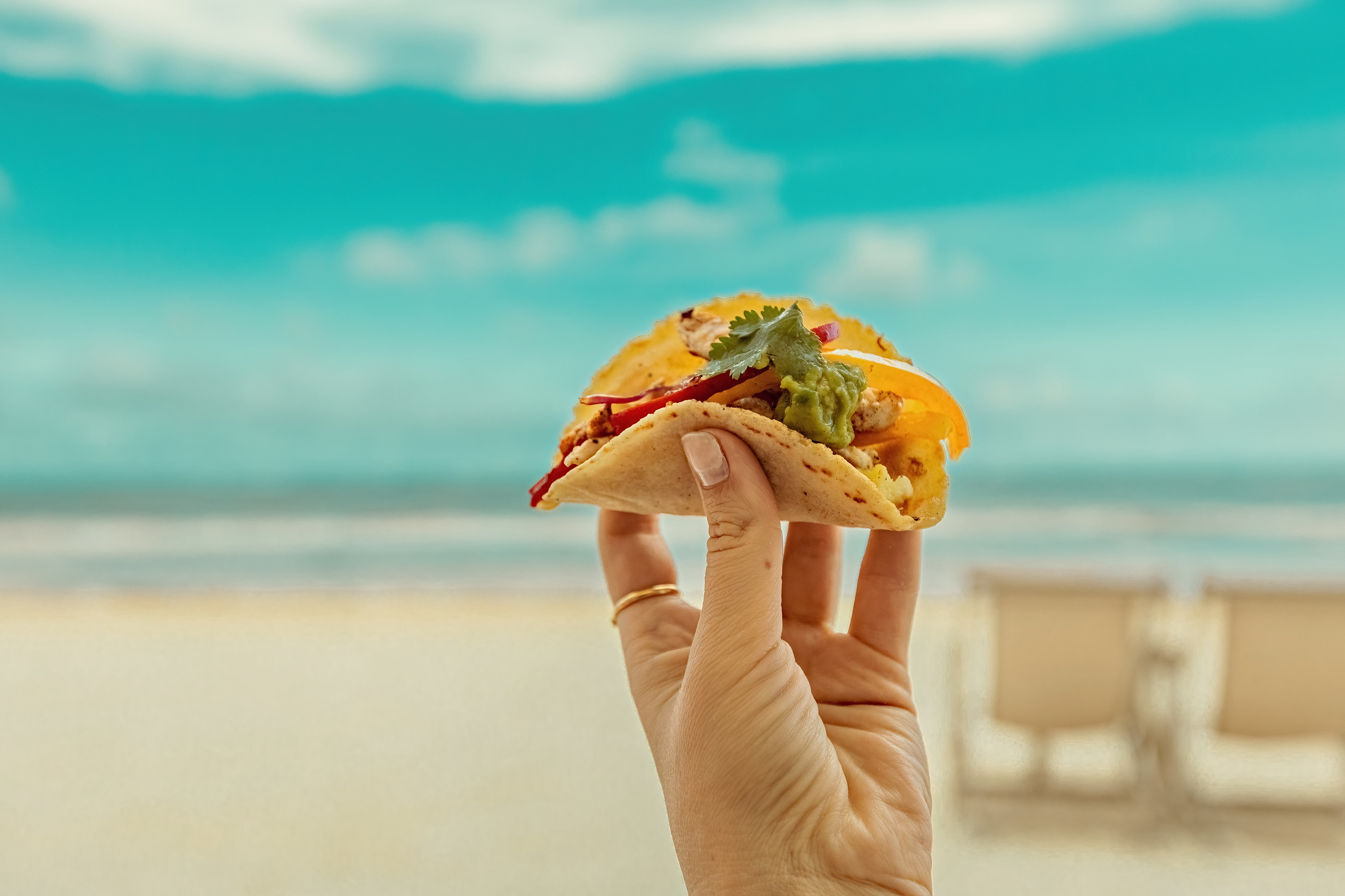 Woman holding a taco in front of the ocean